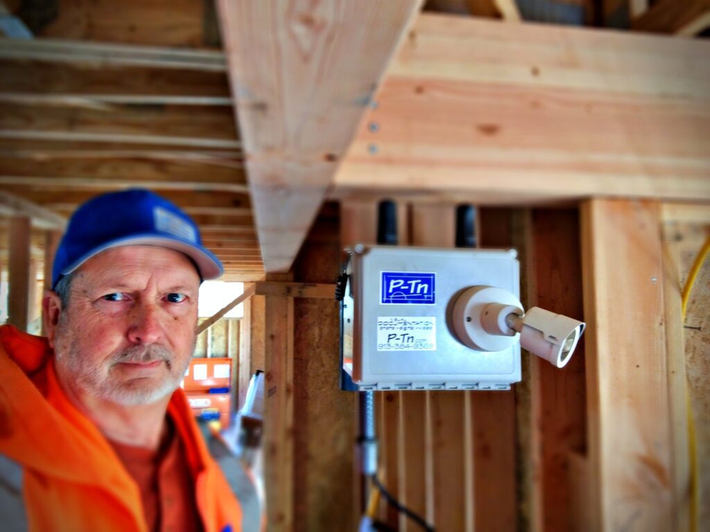 Construction technician with site-monitoring webcam unit inside home build | P-Tn