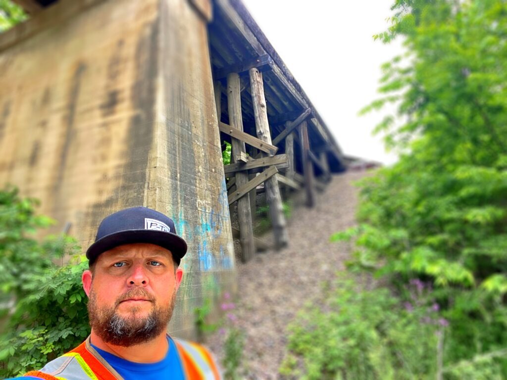 man in orange vest below old bridge | P-Tn