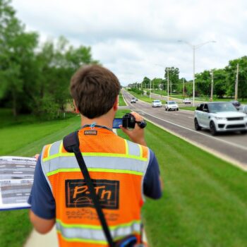could be man alongside road documenting road with camera and construction vest | P-Tn
