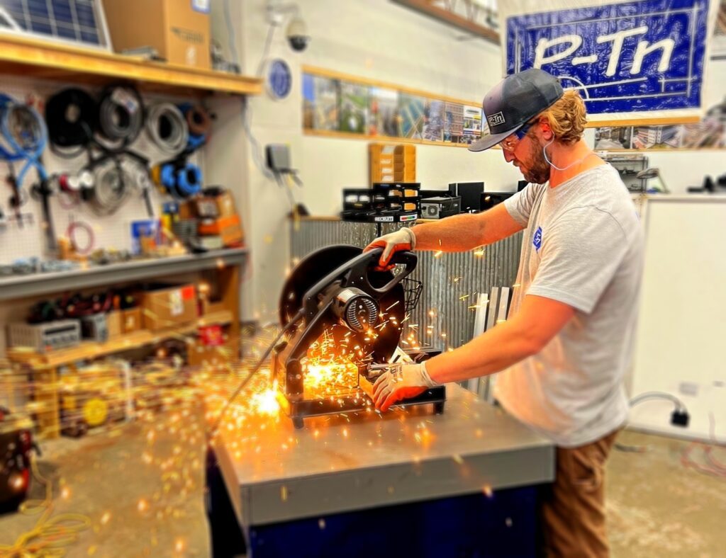 Man uses miter saw with sparks flying with large banner that says P-Tn | P-Tn