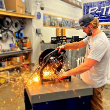 Man uses miter saw with sparks flying with large banner that says P-Tn | P-Tn