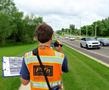 could be man alongside road documenting road with camera and construction vest | P-Tn